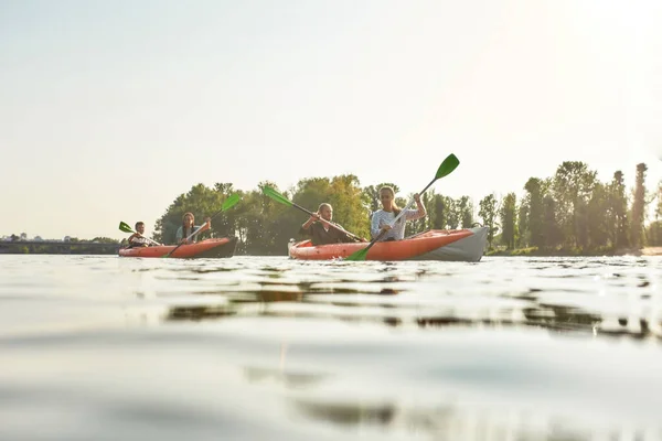 Twee jonge vrienden die enthousiast op een zomerdag samen kajakken in een boot op een rivier — Stockfoto