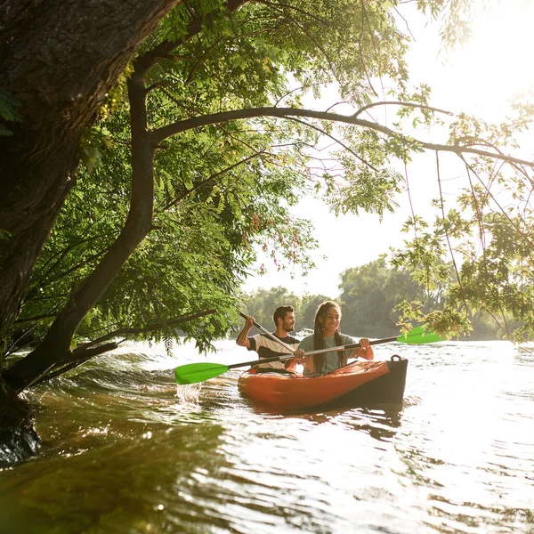 Paar kajakken op de rivier omgeven door bomen, genieten van avontuurlijke ervaring tijdens de zomervakantie — Stockfoto