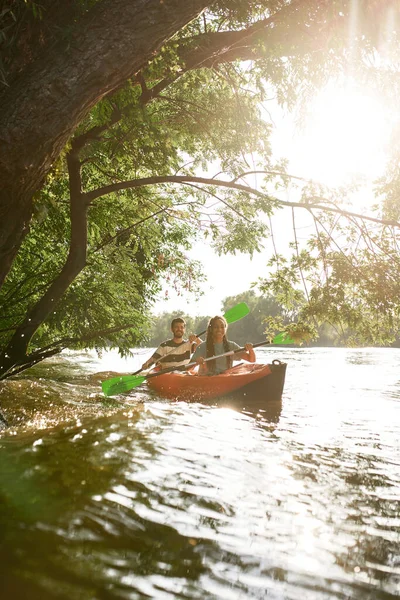 Pár evezés kajak a folyón körül fák, élvezi a kalandos tapasztalat a nyári vakáció — Stock Fotó