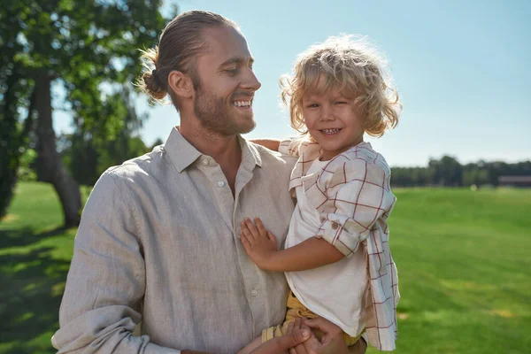 Mutlu genç baba bir yaz günü onunla parkta oynarken oğlunu kucağına alıyor. — Stok fotoğraf
