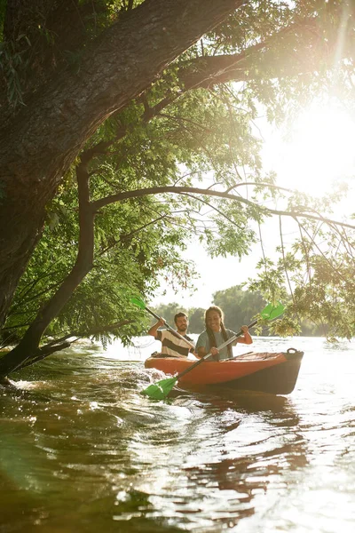 Bote en pareja en el río rodeado de árboles, disfrutando de una experiencia aventurera durante las vacaciones de verano — Foto de Stock