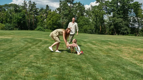 Ευτυχισμένη οικογένεια που διασκεδάζει, παίζοντας ποδόσφαιρο στο γρασίδι στο πάρκο μια καλοκαιρινή μέρα — Φωτογραφία Αρχείου