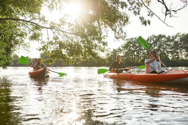 Gente feliz activa divirtiéndose juntos mientras navegan en kayak por el río en un día soleado durante las vacaciones de verano — Foto de Stock