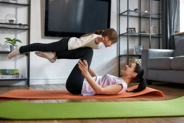 Glad sportig mamma och dotter tränar tillsammans hemma — Stockfoto