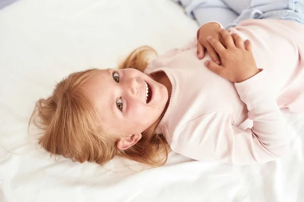 Sorrindo menina criança relaxar na cama aconchegante em casa — Fotografia de Stock