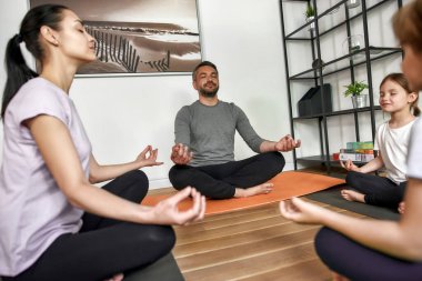 Küçük çocuklu küçük ebeveynler evde yoga yapıyor.