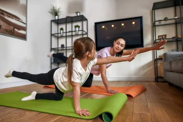 Sağlıklı sporcu anne ve küçük kızı evde birlikte antrenman yapıyor. — Stok fotoğraf