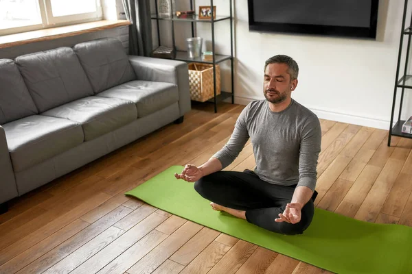 Lugn vit man meditera hemma på yogamattan — Stockfoto