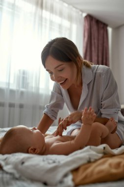 Anne ve bebek hafif yatak odasında oynaşıyor.