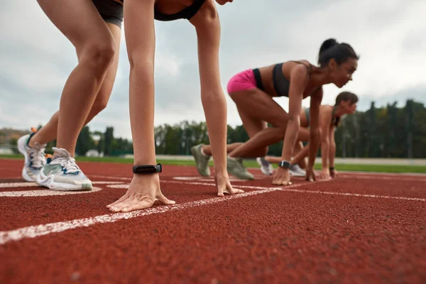 Vista de cerca de corredores femeninos profesionales listos para comenzar la carrera en el campo de atletismo en el estadio — Foto de Stock