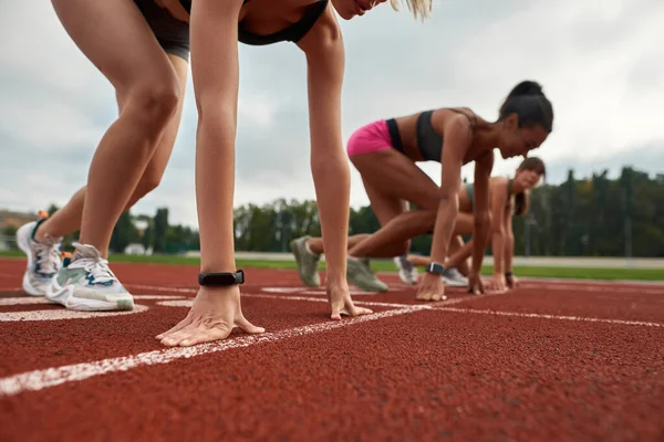 Primer plano de las armas con reloj inteligente de corredor femenino profesional listo para comenzar la carrera en el campo de atletismo en el estadio — Foto de Stock