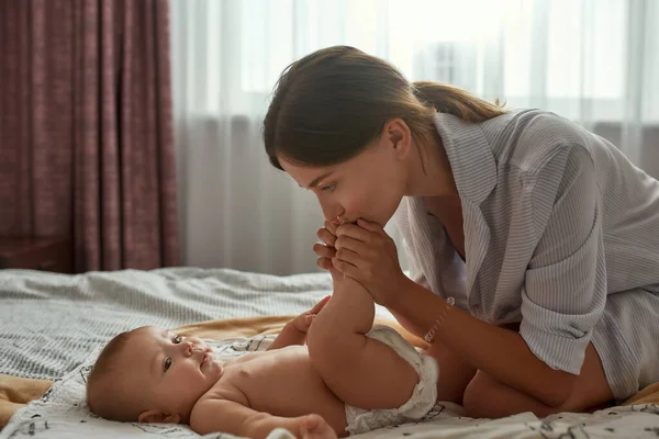 Moeder zoenen met tederheid pasgeboren baby voeten — Stockfoto