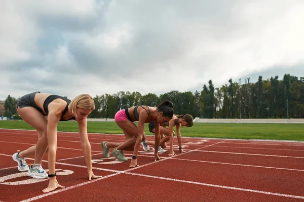 Professionella kvinnliga löpare redo att starta loppet på banan på stadion — Stockfoto