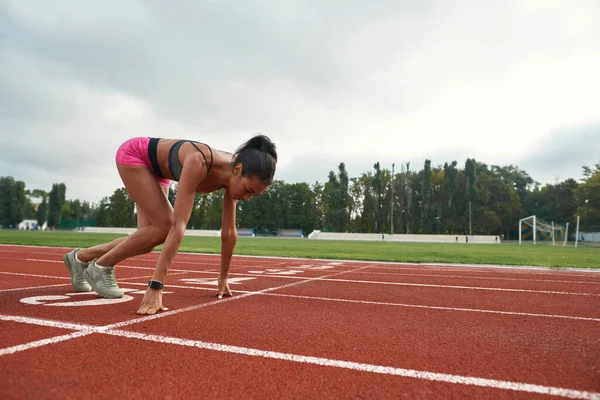 Corredor femenina joven profesional en la carrera de salida de ropa deportiva en el campo de atletismo en el estadio — Foto de Stock