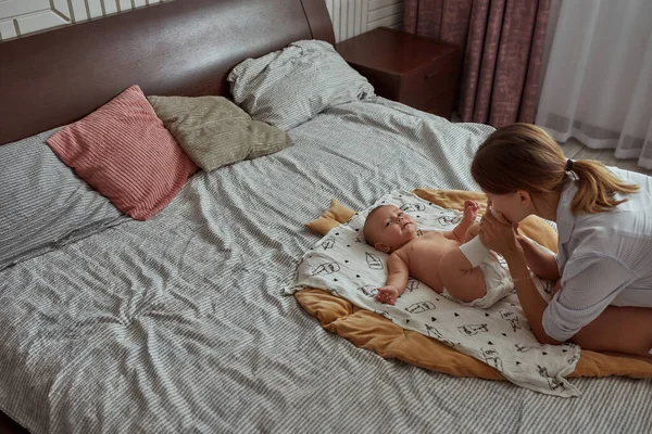 Ibu muda lembut mencium kaki babys di kaus kaki — Stok Foto