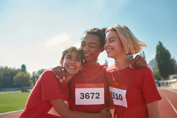 Porträtt av unga professionella kvinnliga löpare bär t-shirts med nummer ser glada ut när de står tillsammans, redo för loppet — Stockfoto