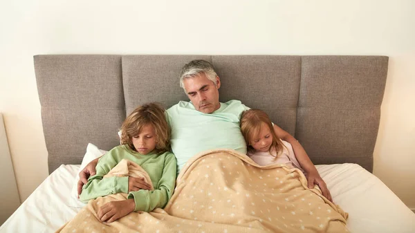 Ongezonde zieke vader en kinderen ontspannen slapen in bed — Stockfoto