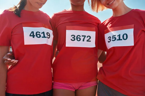 Beskuren bild av grupp kvinnliga löpare bär t-shirts med nummer står tillsammans, redo att starta loppet — Stockfoto