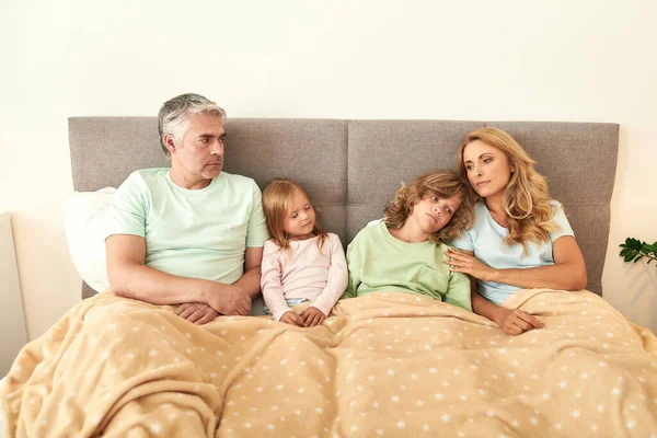 Familia enferma y cansada con niños descansan en la cama — Foto de Stock