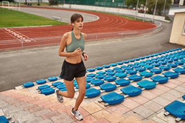Aktif genç sporcunun tam boy çekimi. Formda kalıyor, stadyumda antrenman yapıyor.