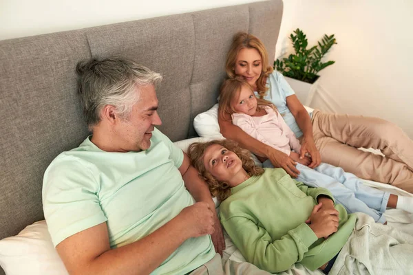 Familia feliz con los niños relajarse en la cama en el encierro — Foto de Stock