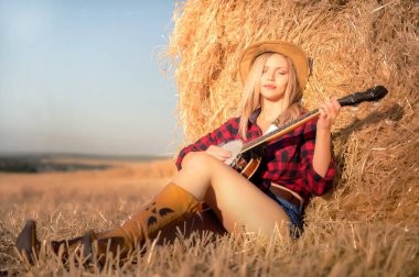 Bançolu bir köylü kızı samanlığın yanındaki bir tarlada oturuyor. .