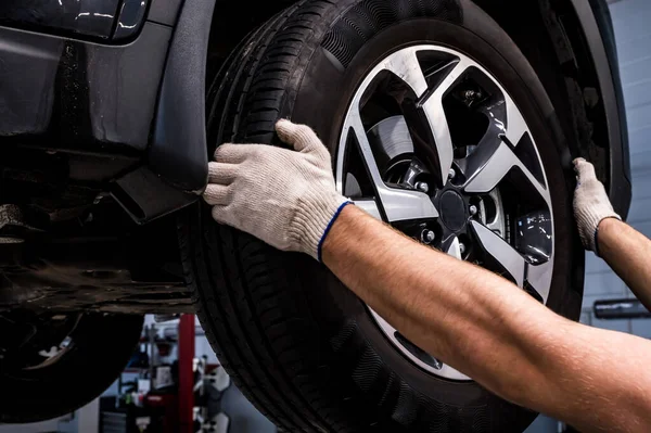 Close up of mechanic removes a wheel from car Stock Picture