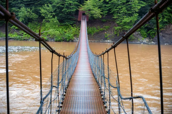 Jembatan logam sempit kaki melintasi sungai di musim gugur — Stok Foto