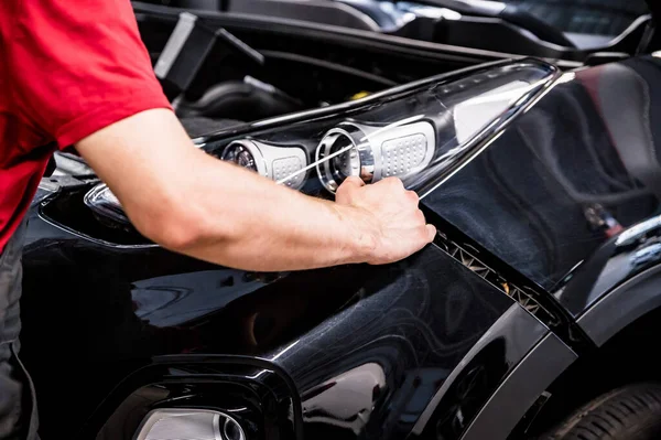 Close-up of mechanic hands dismantling the bumper of the car — Stock Photo, Image