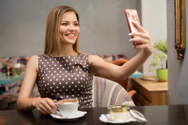 Kafede cep telefonu kullanan güzel, rahat bir kadın. Selfie yapıyorum.