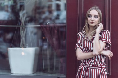 Uzun saçlı genç manken eski kafenin önünde poz veriyor.