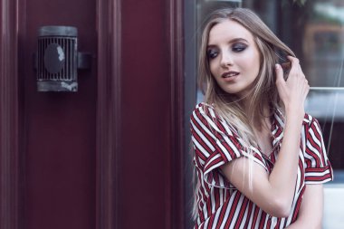 Uzun saçlı genç manken eski kafenin önünde poz veriyor.