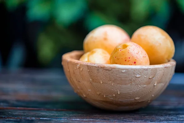 Fresh ripe apricots in wooden bowl outdoors. Blurred background — Stock Photo, Image