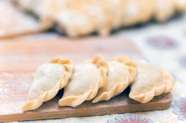 Ahşap bir tahtanın üzerinde duran patatesli hamur köftelerini kapat.