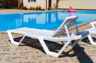 Yüzme havuzunun yanında boş plastik iskemle.