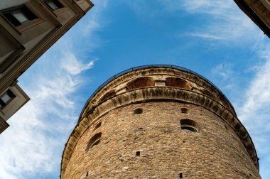 Mavi gökyüzüne karşı klasik binalarla çevrili aşağıdan Galata Kulesi 'nin görüntüsü