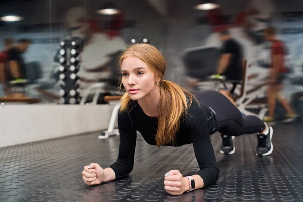 Atractiva joven mujer hace ejercicio de tablón en el gimnasio — Foto de Stock