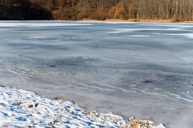 Kar ve buzla kaplı bir nehir kıyısı.