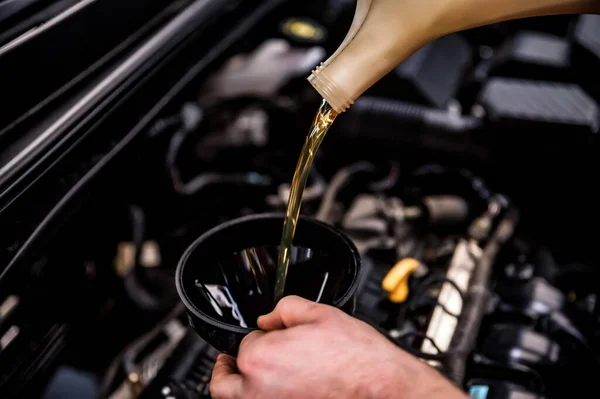 Nahaufnahme eines Mechanikers, der Öl mit einem Trichter hinzufügt — Stockfoto