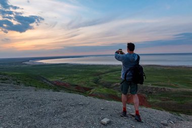 Arkaya bakan genç erkek yürüyüşçü denize ve ufka bakıyor