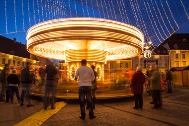 24 Aralık 2014 Sibiu, Romanya. Noel ışıkları, atlıkarınca taşıma, Noel Fuarı, ruh hali ve mavi saatinde dolaşan insanlar