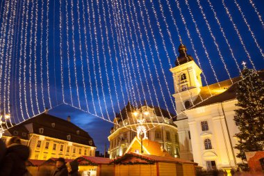 24 Aralık 2014 Sibiu, Romanya. Noel ışıkları, atlıkarınca taşıma, Noel Fuarı, ruh hali ve mavi saatinde dolaşan insanlar