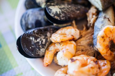 Tabak pişmiş midye, karides, kalamar ve balık