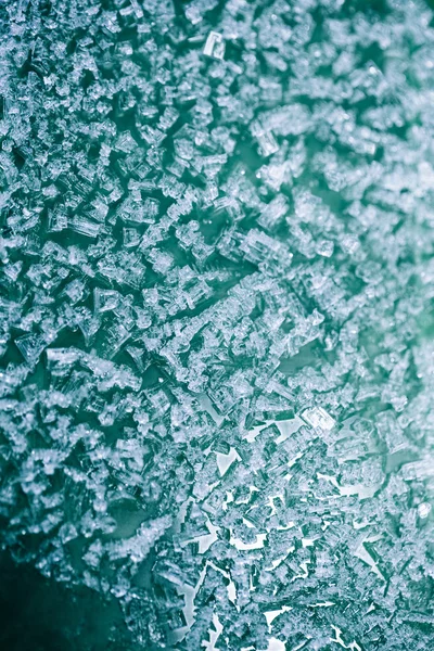 Pequenos pedaços de gelo em uma superfície de plástico, fundo de inverno e textura — Fotografia de Stock