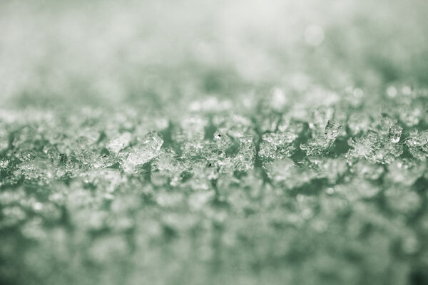 Tiny ice pieces on a plastic surface, winter background and texture