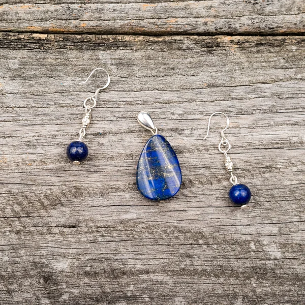 Silver jewels with colorful precious stones on a wooden surface