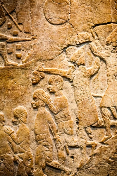 29. 07. 2015, LONDRES, ROYAUME-UNI, MUSÉE BRITANNIQUE - Détails du mur assyrien montrant des bâtiments égyptiens en arrière-plan. Au premier plan, les prisonniers nubiens portent des coiffes de plumes — Photo