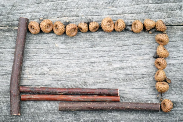 Still life composition/ frame with tiny acorns and wooden sticks on an old wooden surface. Beautiful vintage composition — Stock Photo, Image