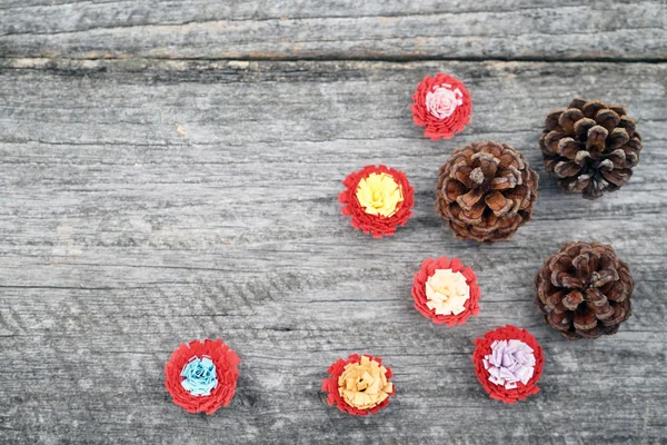 Eski bir ahşap yüzey üzerinde quilling tekniği ve çam kozalağı ile yapılan renkli kağıt çiçekler ile natürmort kompozisyon. Güzel vintage Noel kompozisyon — Stok fotoğraf