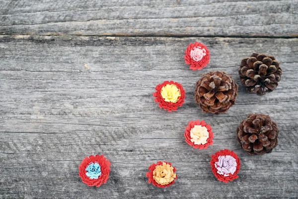 Eski bir ahşap yüzey üzerinde quilling tekniği ve çam kozalağı ile yapılan renkli kağıt çiçekler ile natürmort kompozisyon. Güzel vintage Noel kompozisyon — Stok fotoğraf